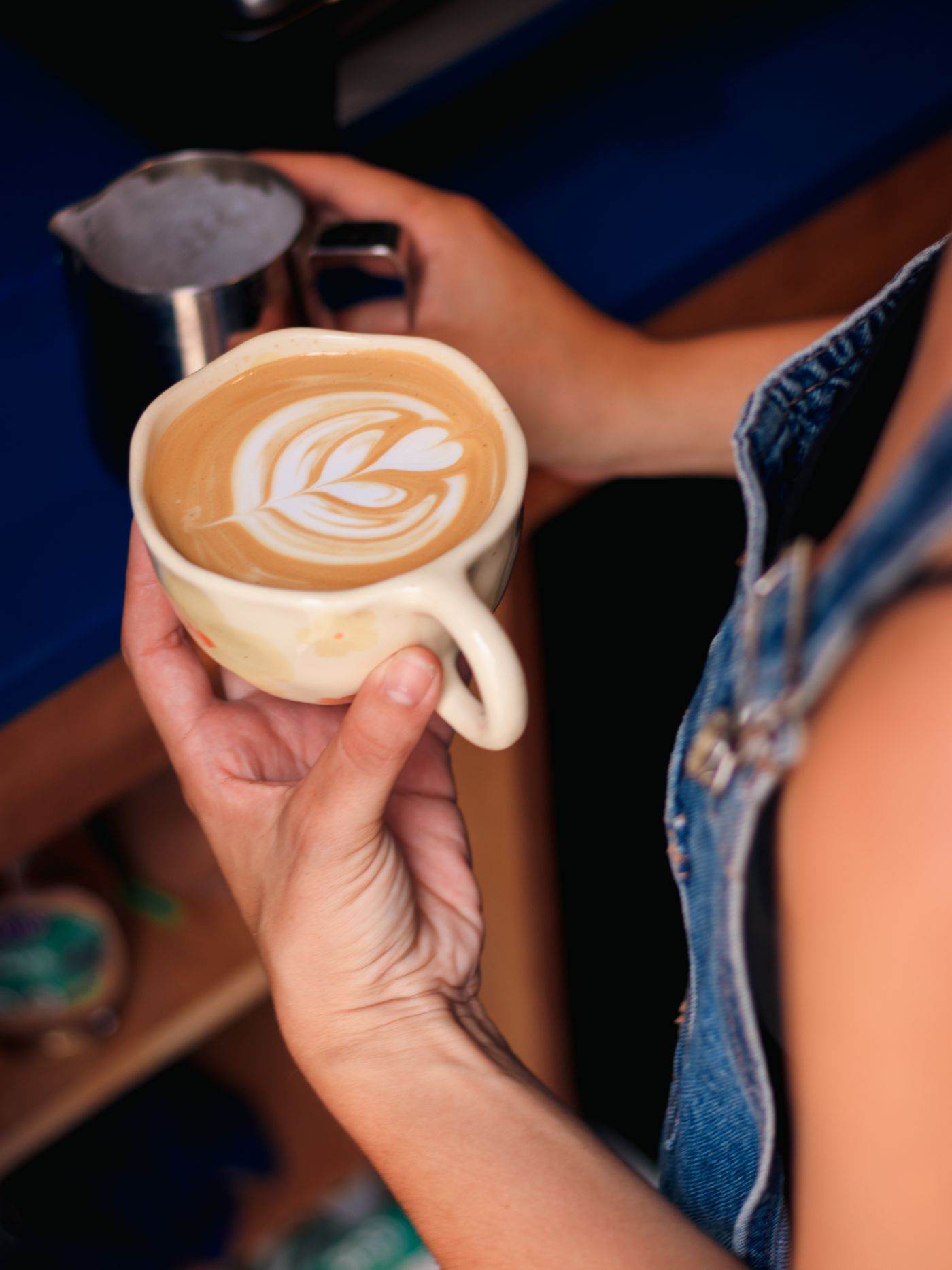 Hands pouring latte art at the counter.