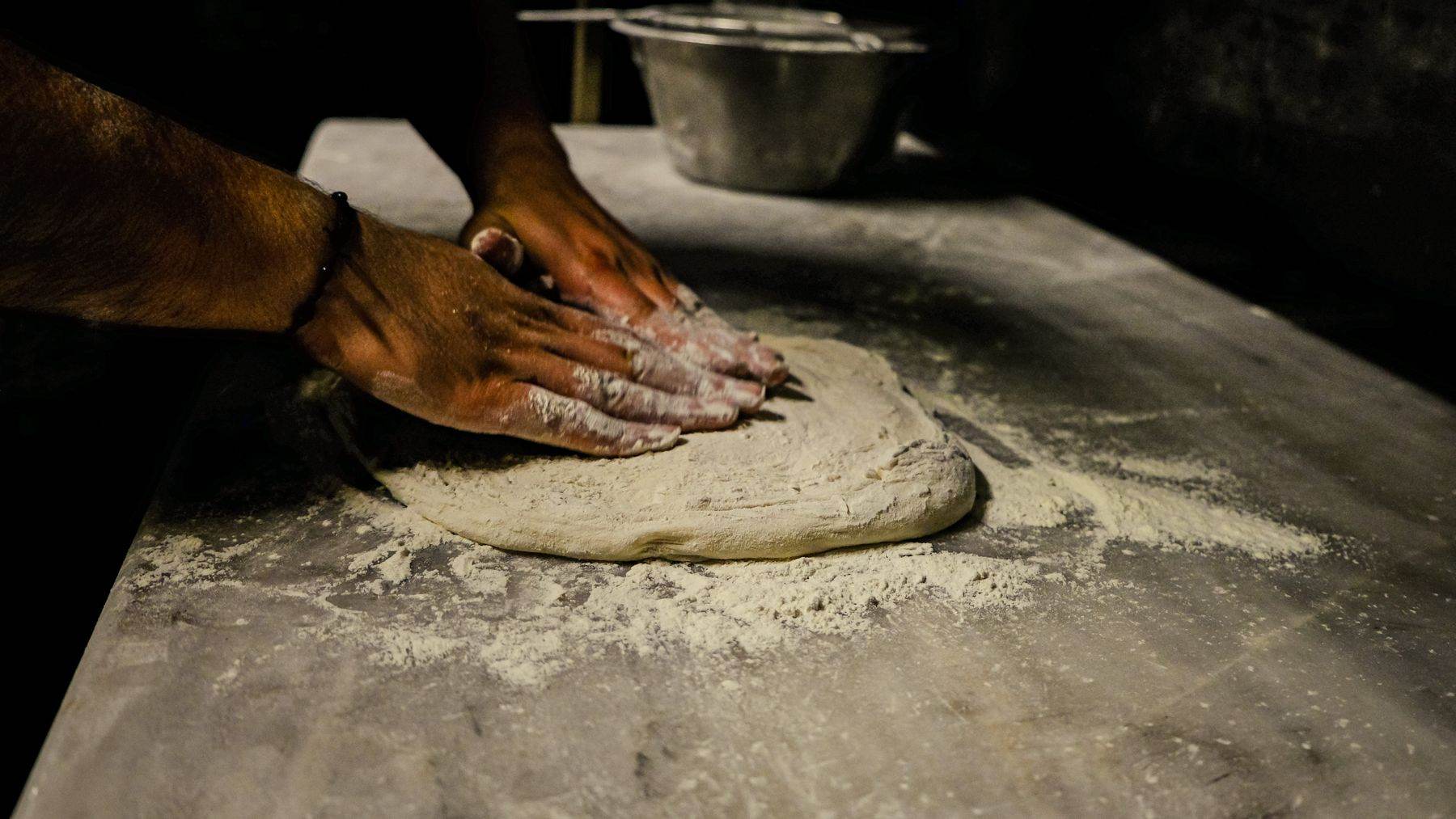 Hands shaping dough on the bench.